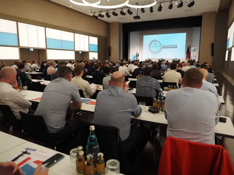 on this picture you can see a seminar room full of people sitting and listening a lecture at the stamping technology congress.