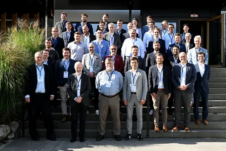 The photo shows all participants in a group photo on an outdoor staircase.